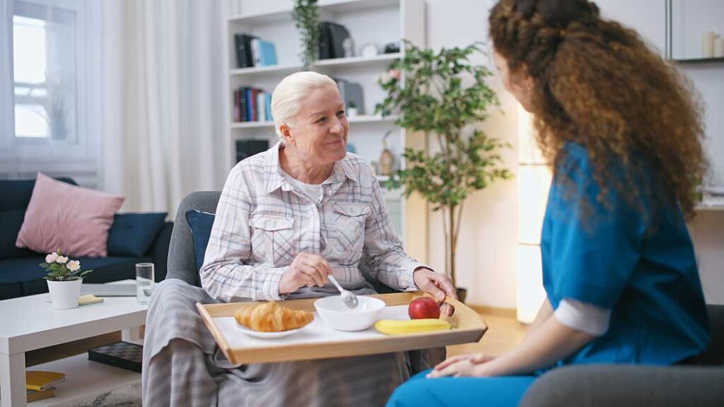 Elderly individuals enjoying a group activity with attentive caregivers in a cozy, well-lit common room.