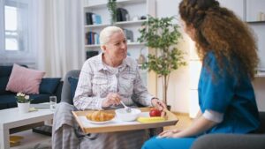Elderly individuals enjoying a group activity with attentive caregivers in a cozy, well-lit common room.