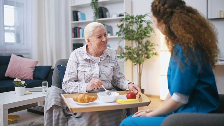 Elderly individuals enjoying a group activity with attentive caregivers in a cozy, well-lit common room.
