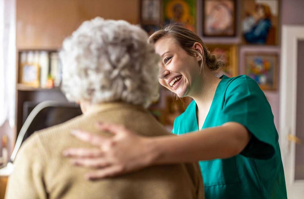 Older adults sitting together around a table, laughing and chatting over coffee in a bright communal room.