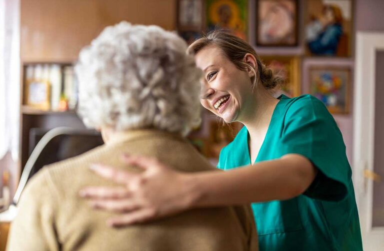 Older adults sitting together around a table, laughing and chatting over coffee in a bright communal room.